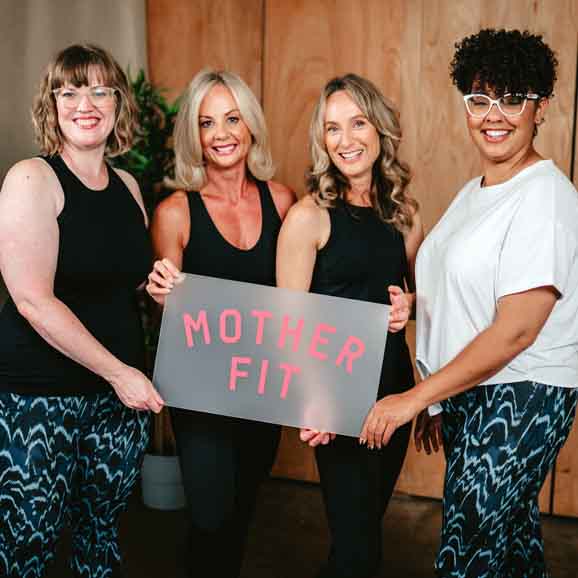 Michelle holding a Mother Fit sign